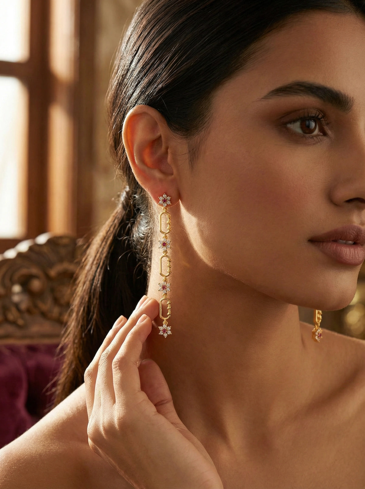 woman wearing 18k gold plated earrings with floral details, indoors.