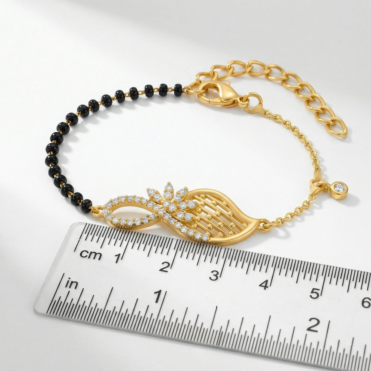 18k gold plated bracelet with black beads on a ruler for size reference