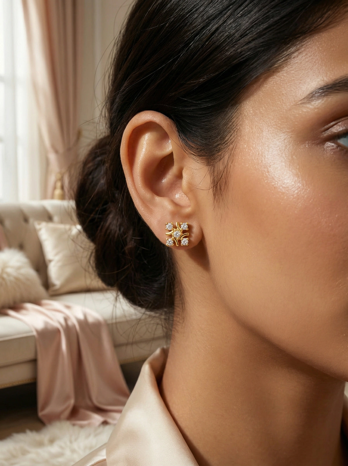 close-up of a woman wearing 18k gold plated earrings with a blurred indoor background
