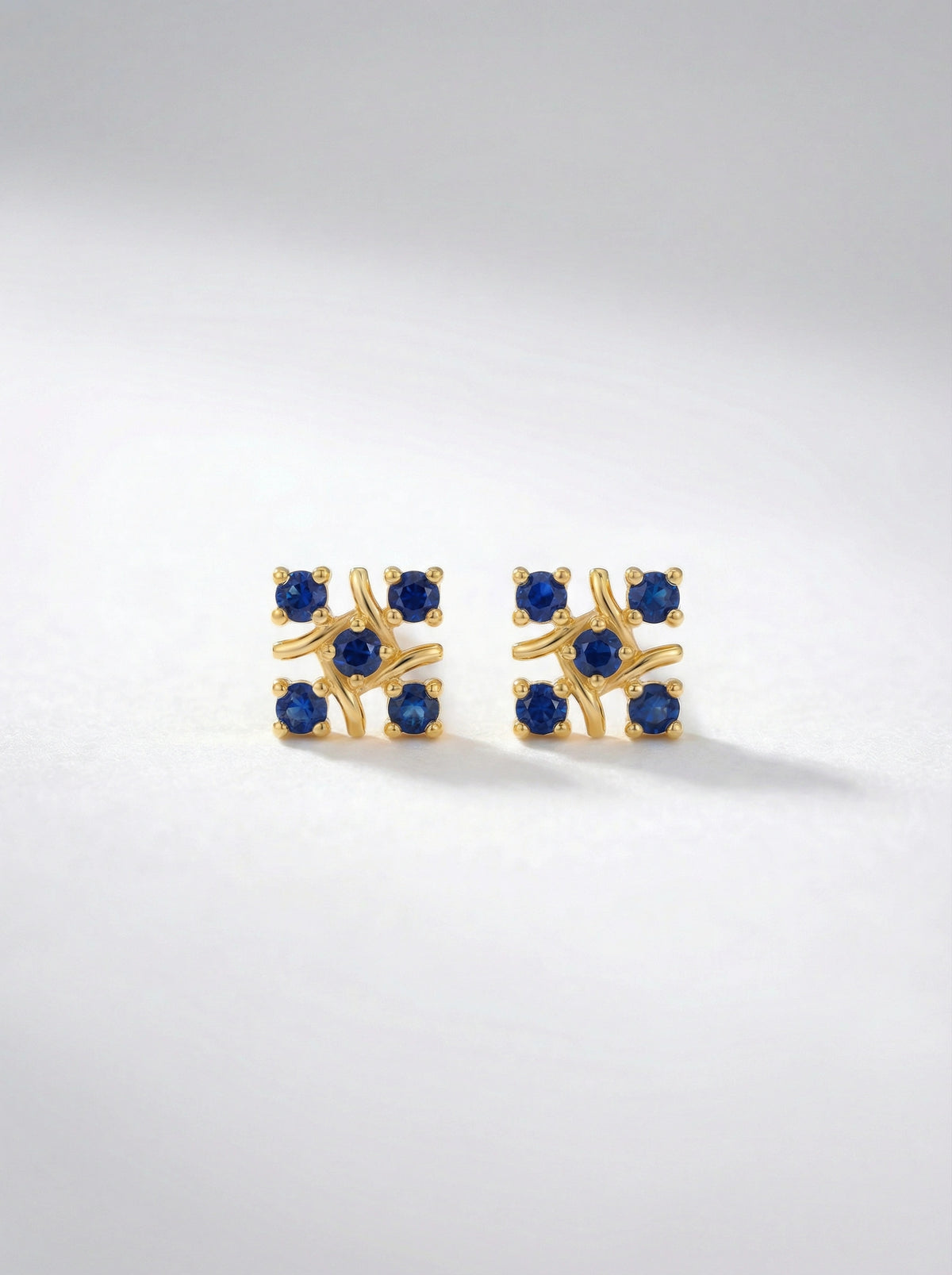 `8k gold plated earrings with blue gemstones on a light gray background