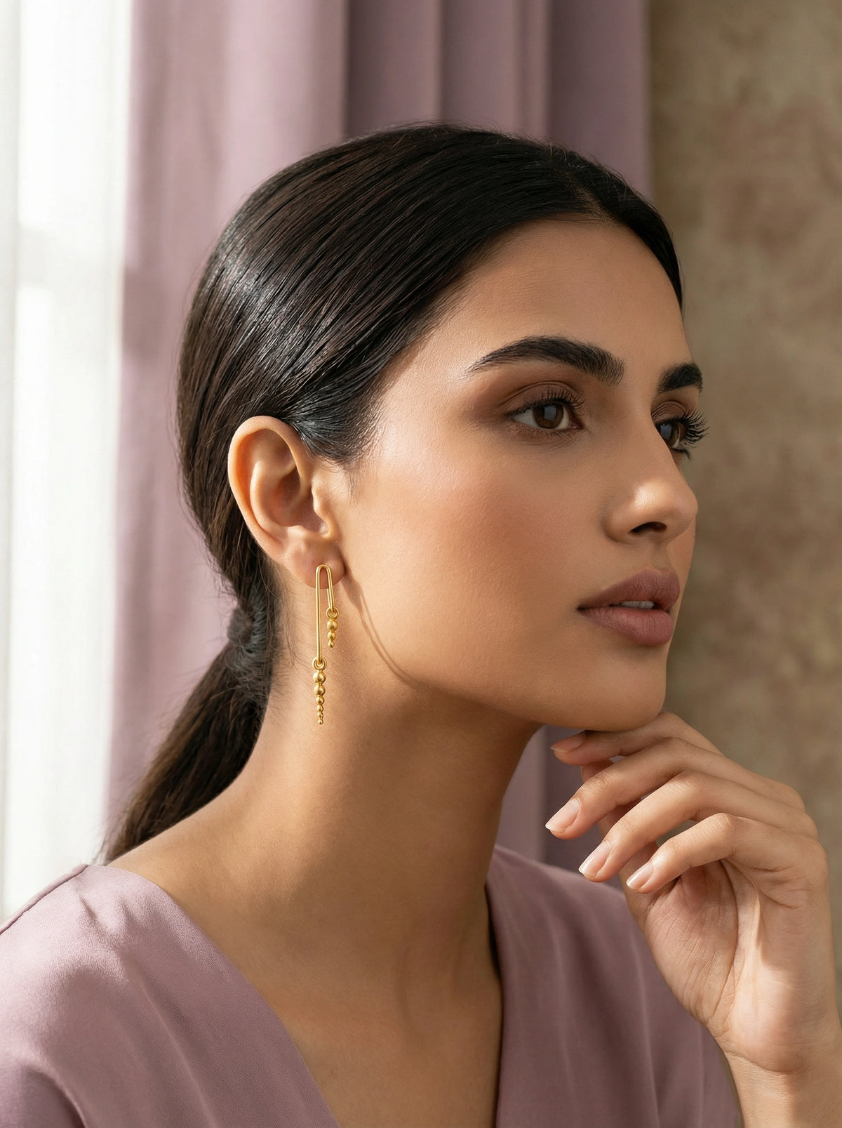 woman wearing  18k gold plated earrings with a soft focus background