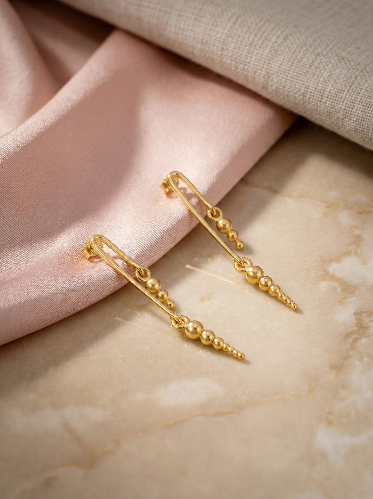 18k gold plated chain earrings on a soft fabric background