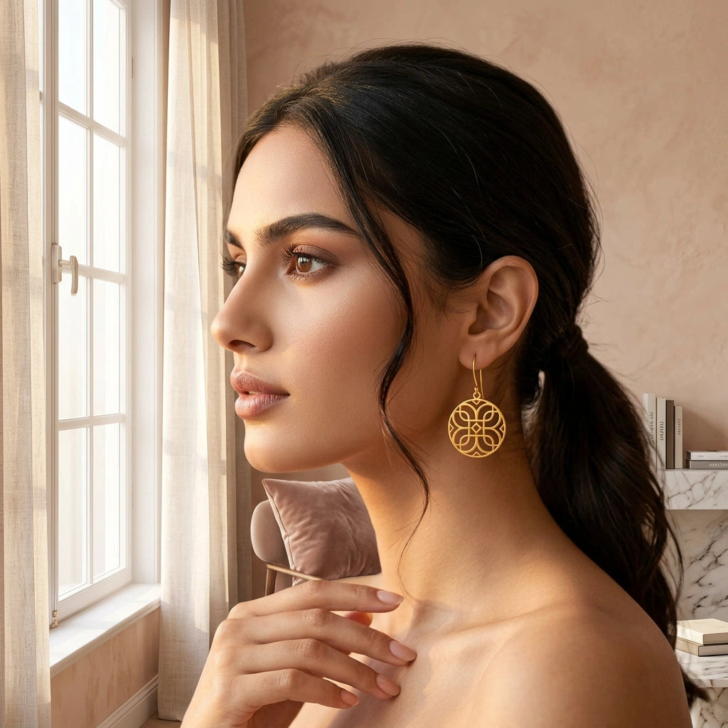 woman wearing  18k gold plated earrings in a softly lit room