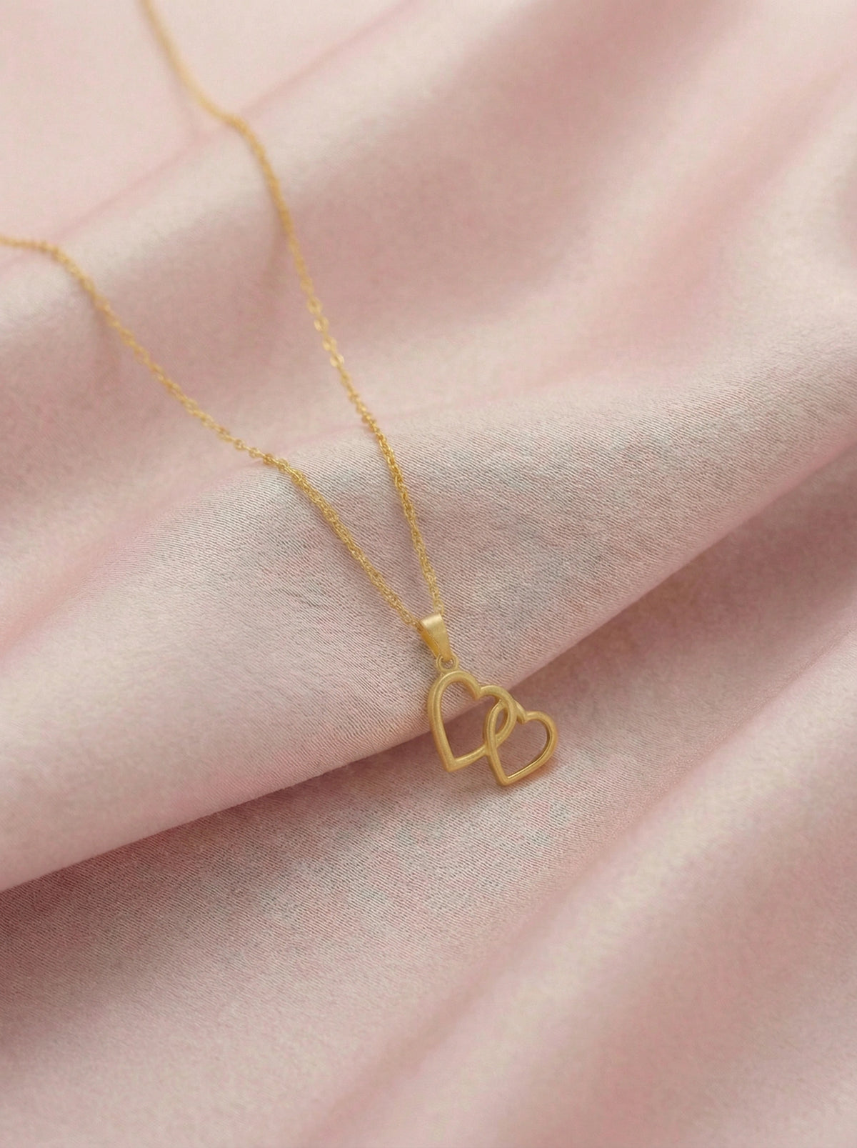 18k gold plated necklace with a heart pendant on a pink fabric background