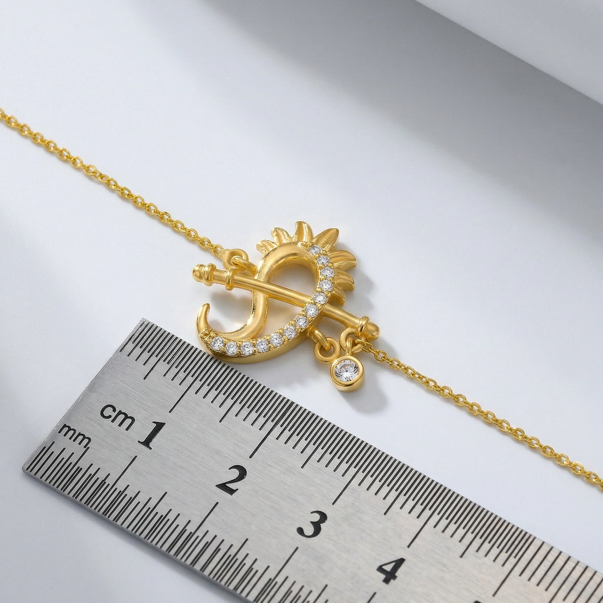 18k gold plated necklace with a decorative pendant next to a ruler for scale on a light gray background
