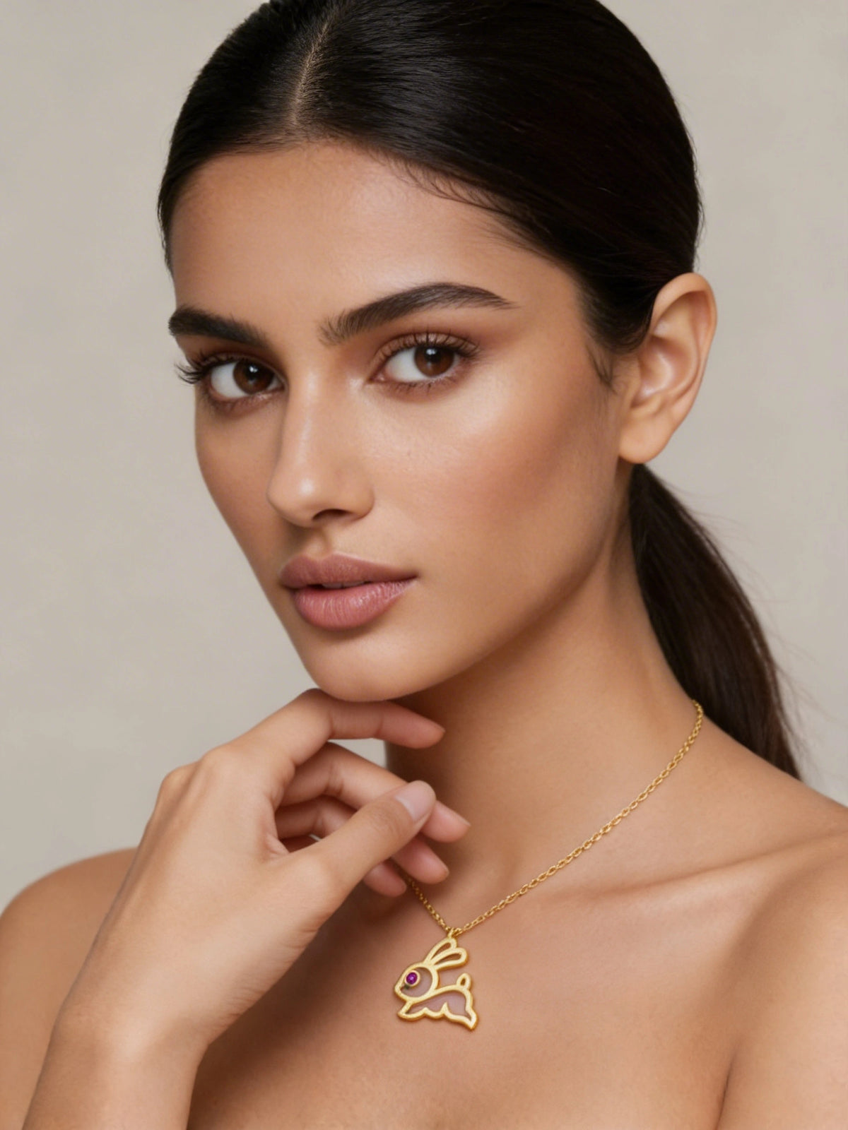 woman wearing a 18k  gold plated necklace with a pendant against a neutral background