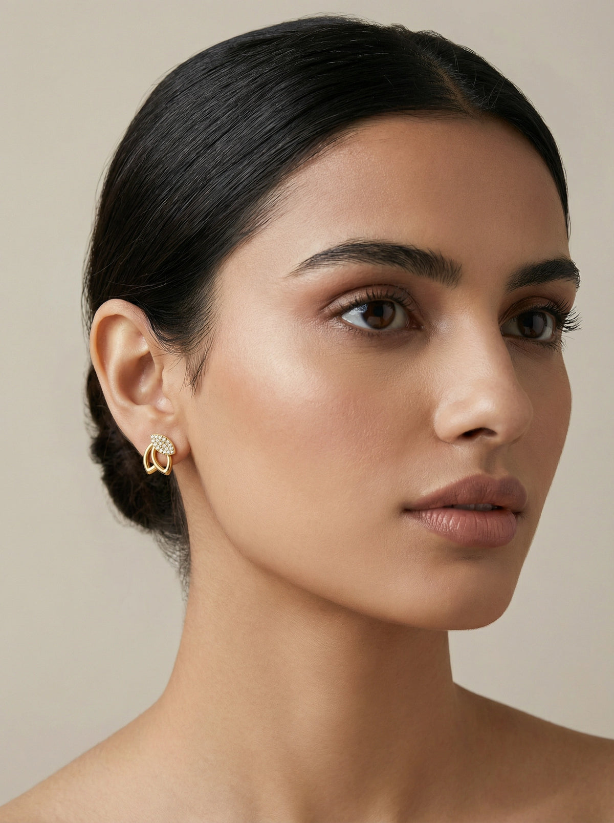 close-up of a woman wearing  18k  gold plated hoop earrings against a neutral background