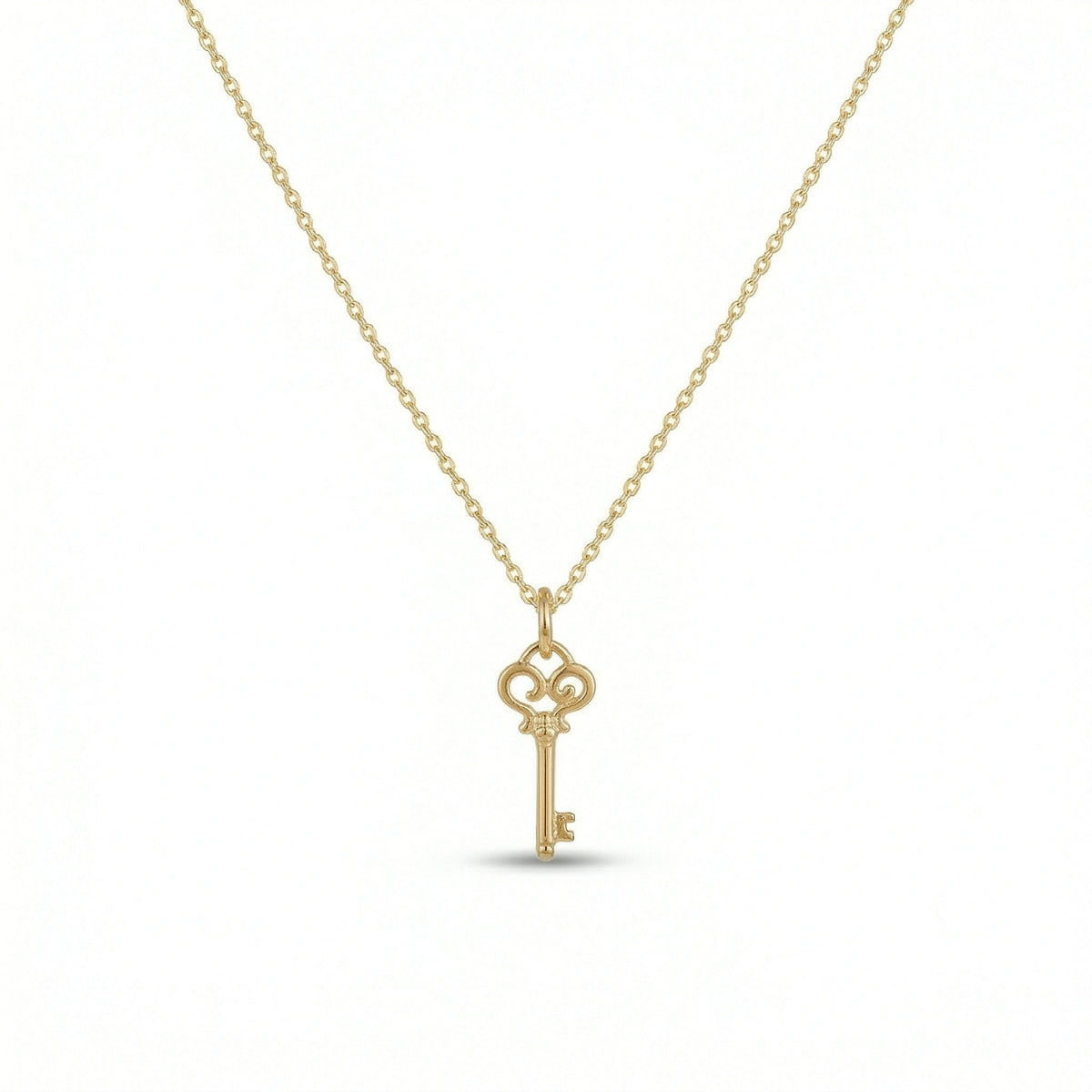 18k Gold  plated  key-shaped pendant on a chain against a white background