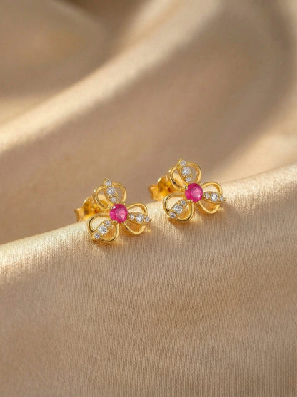 18k Gold plated flower-shaped earrings with pink gemstones on a beige fabric background