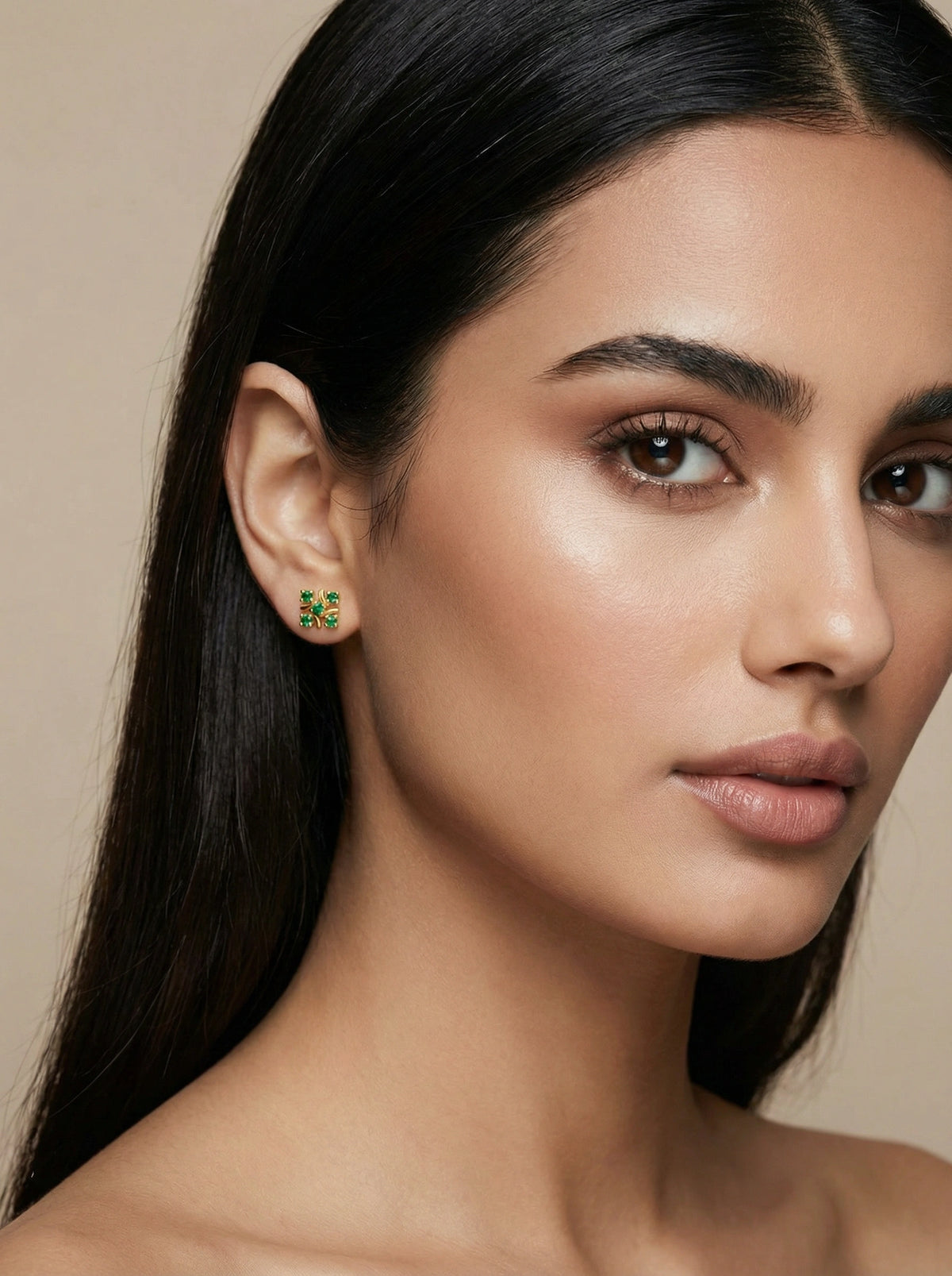 close-up of a woman wearing a 18k gold plated  small  earring with a beige background