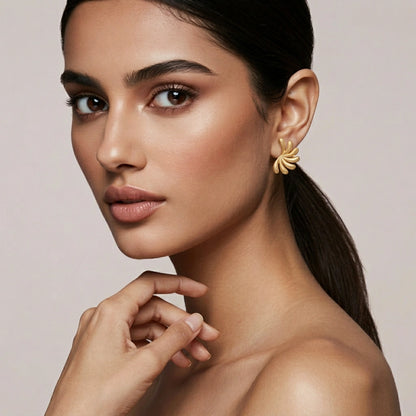 Woman wearing 18k  gold plated earrings with a neutral background