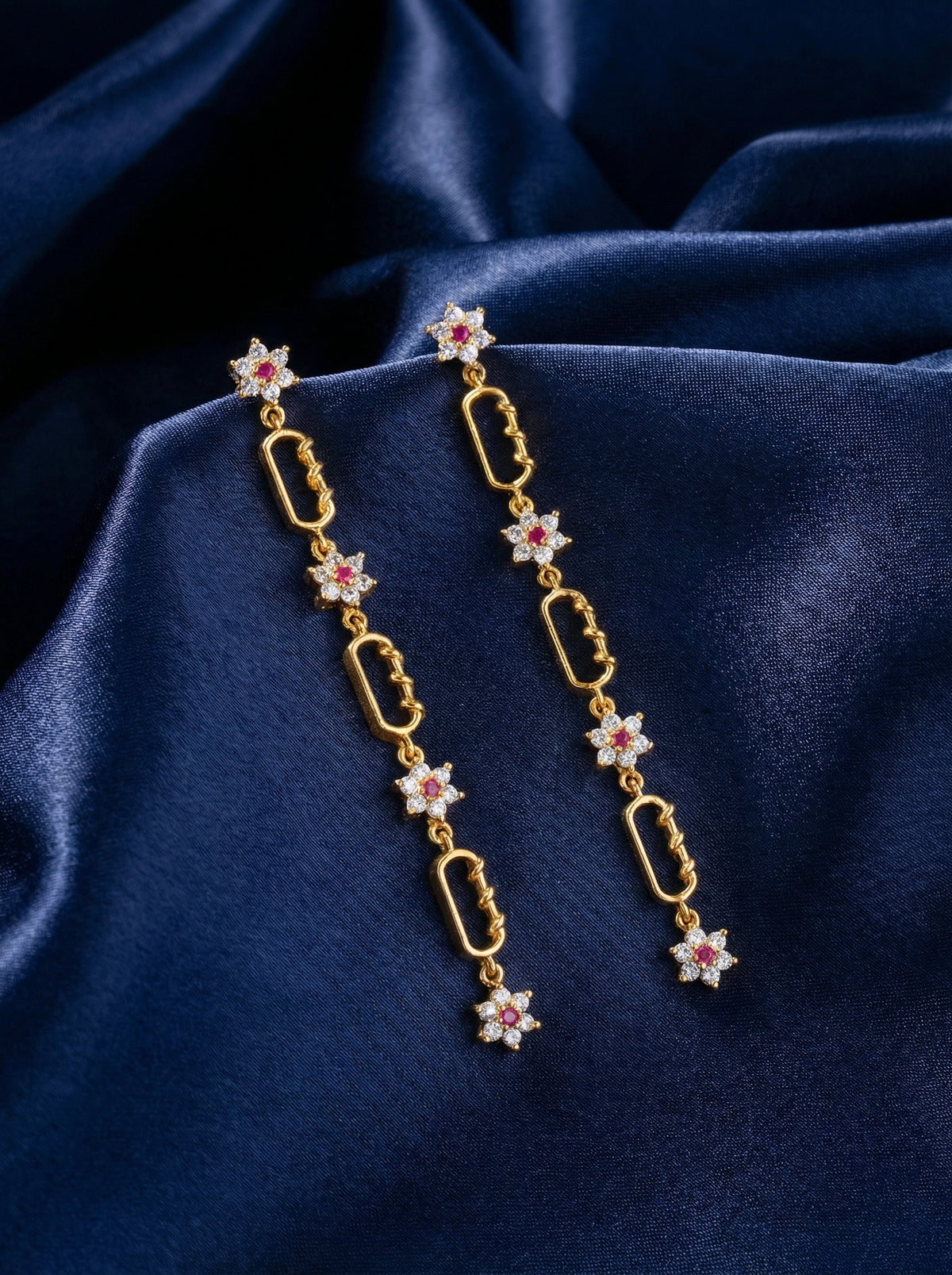 18k gold plated earrings with floral designs on a blue fabric background