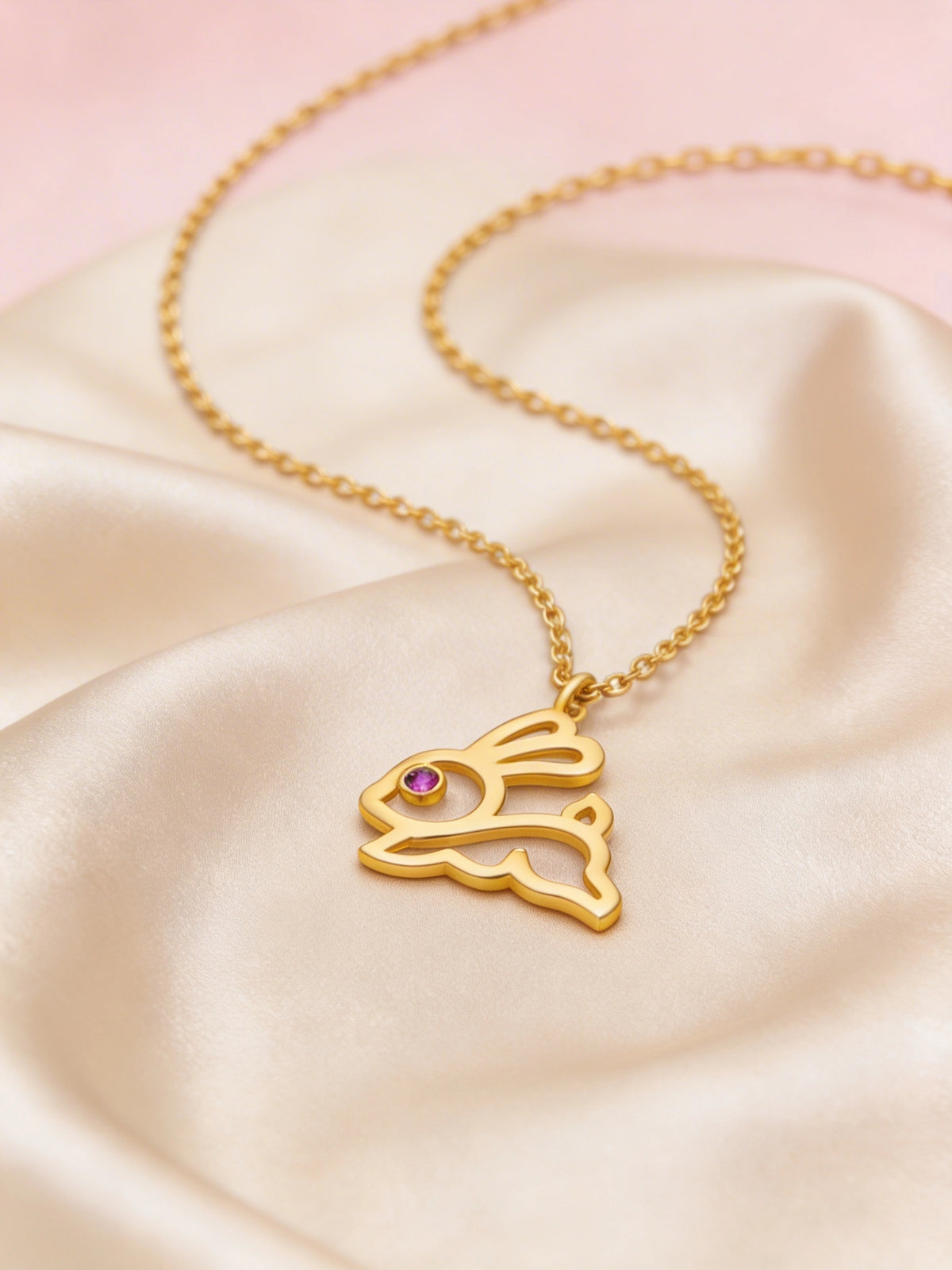 18k gold plated necklace with a rabbit pendant on a pink satin background
