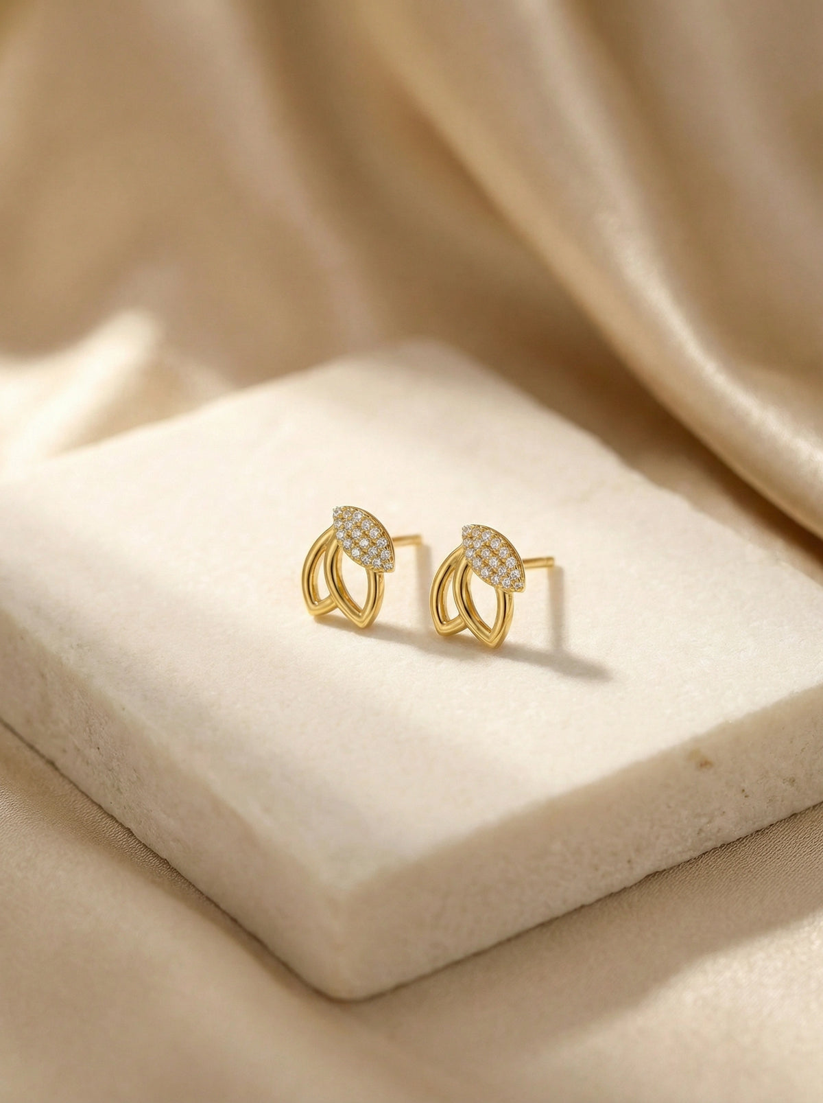 18k gold plated earrings with heart design on a beige fabric background