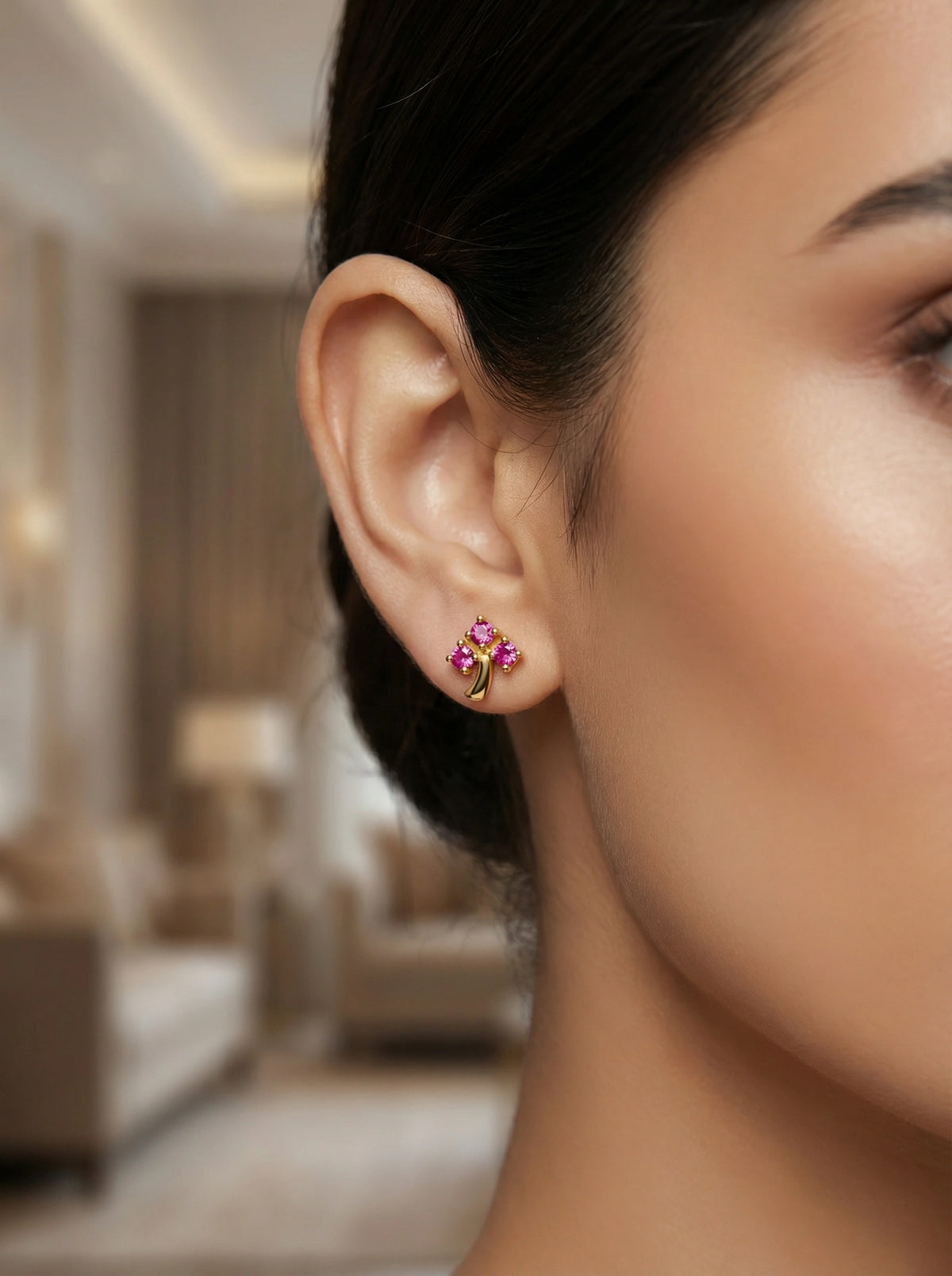 close-up of a woman wearing a floral 18k gold plated earring in an indoor setting