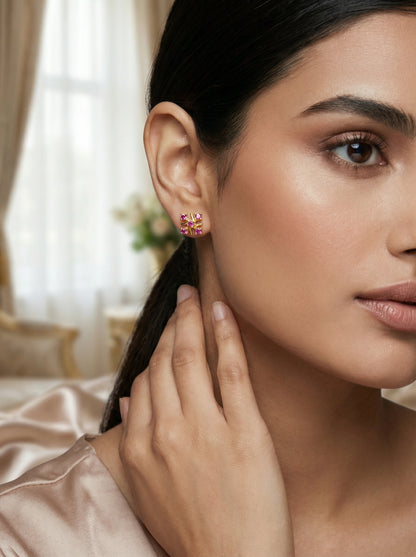 Close-up of a woman wearing 18k gold plated earrings with a blurred indoor background