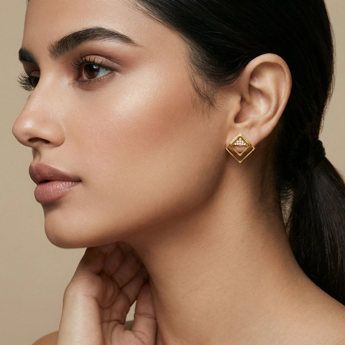 close-up of a woman wearing 18k gold plated earrings with a neutral background