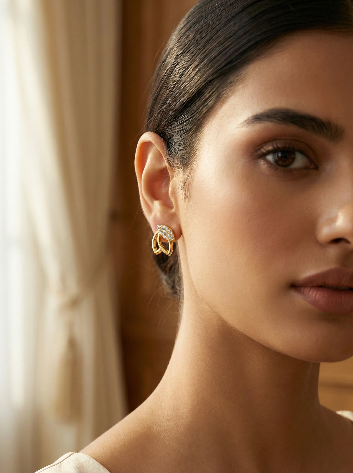 close-up of a woman wearing 18k gold plated hoop earrings with a blurred background