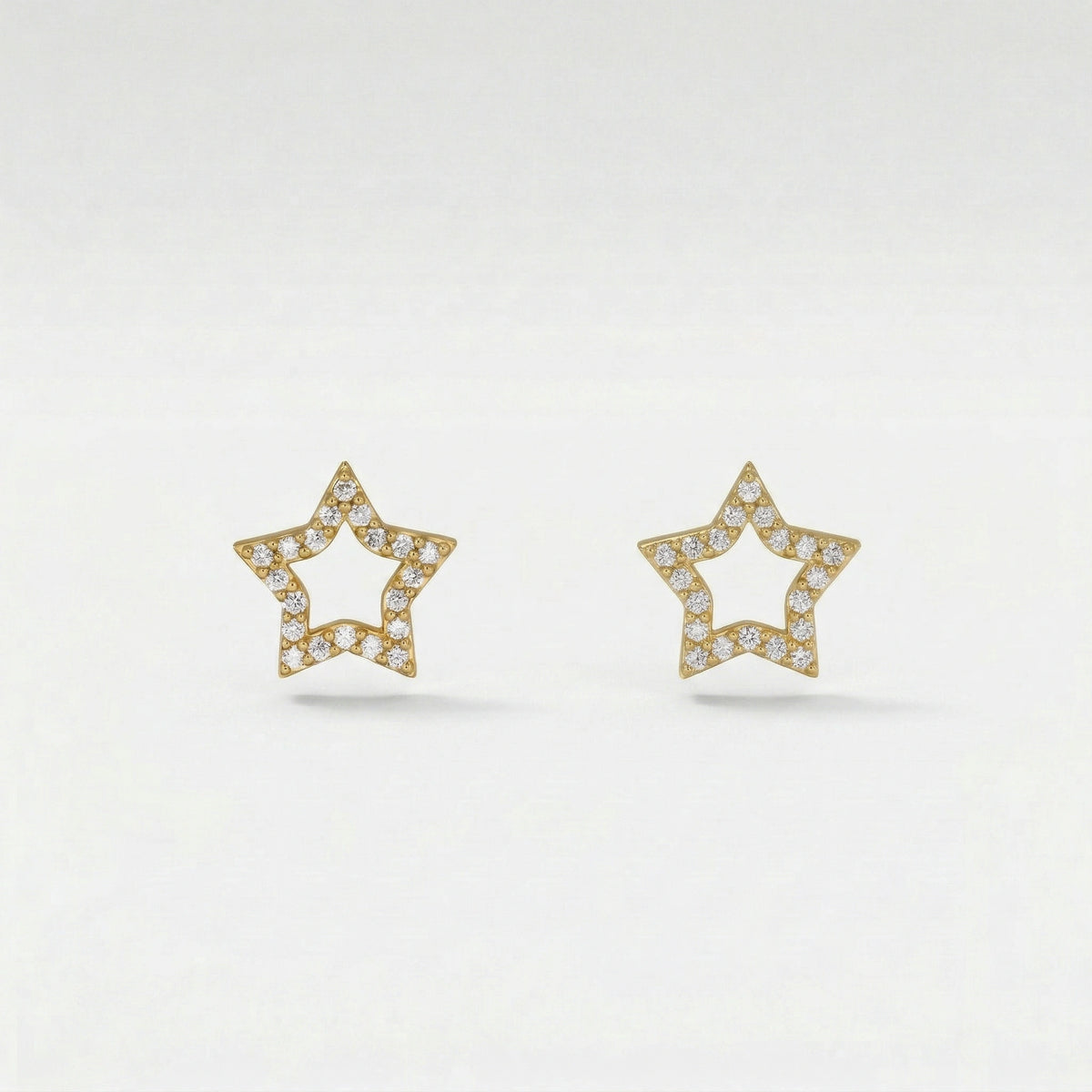 Star-shaped 18k gold plated earrings with diamond accents on a light gray background