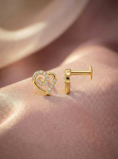 18k Gold plated heart-shaped earring on a person's ear with a soft pink background