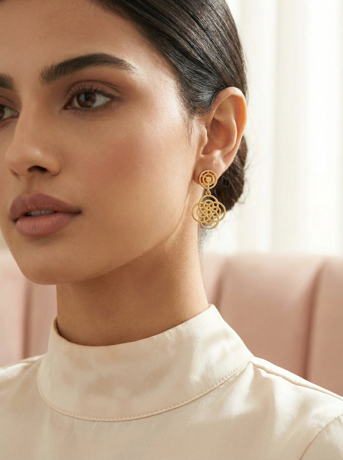 close-up of a woman wearing 18k gold plated  earrings with a blurred background