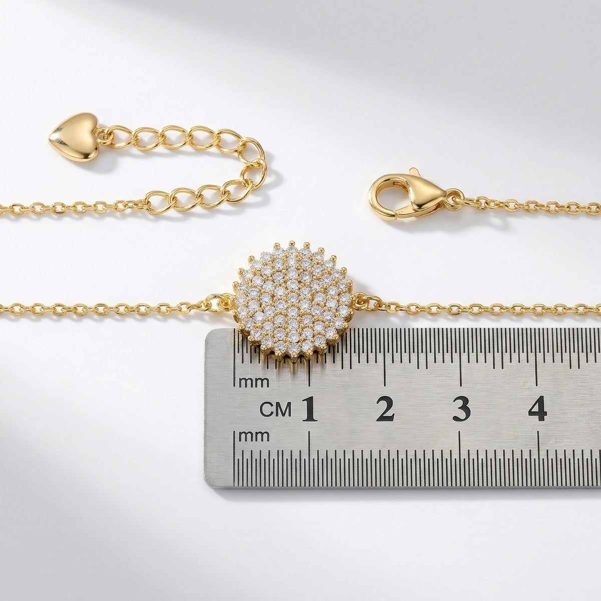 18k gold plated bracelet with a decorative clasp on a ruler for size reference