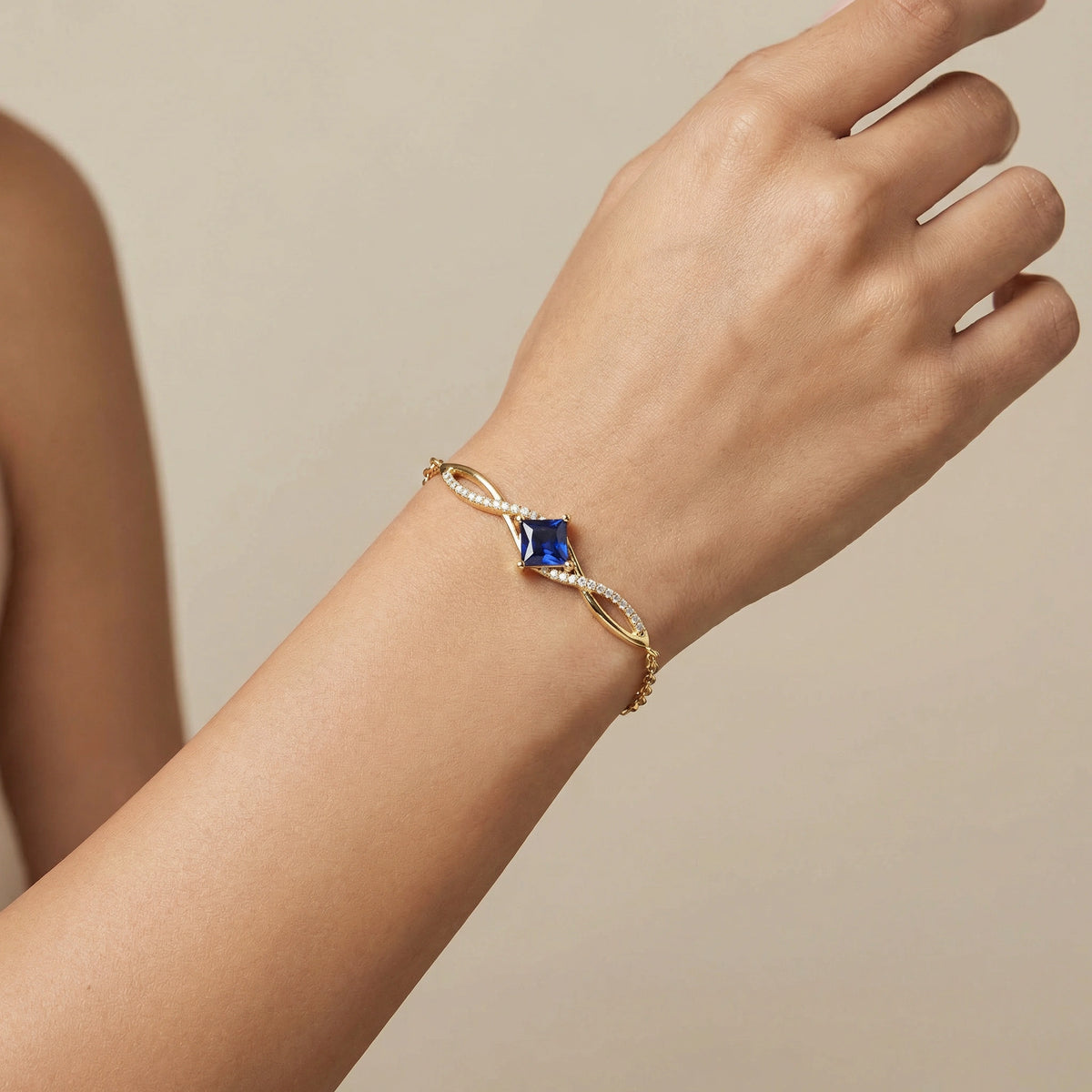 18kgold  plated bracelet with a blue gemstone on a wrist against a beige background