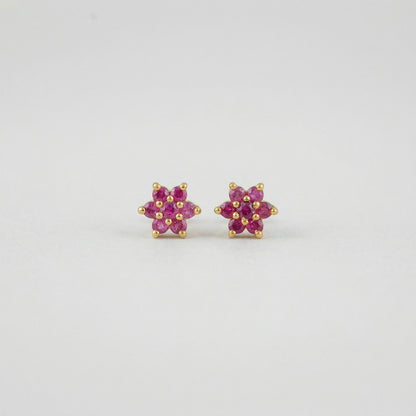 Pair of flower-shaped 18k gold plated  earrings with pink stones on a light gray background