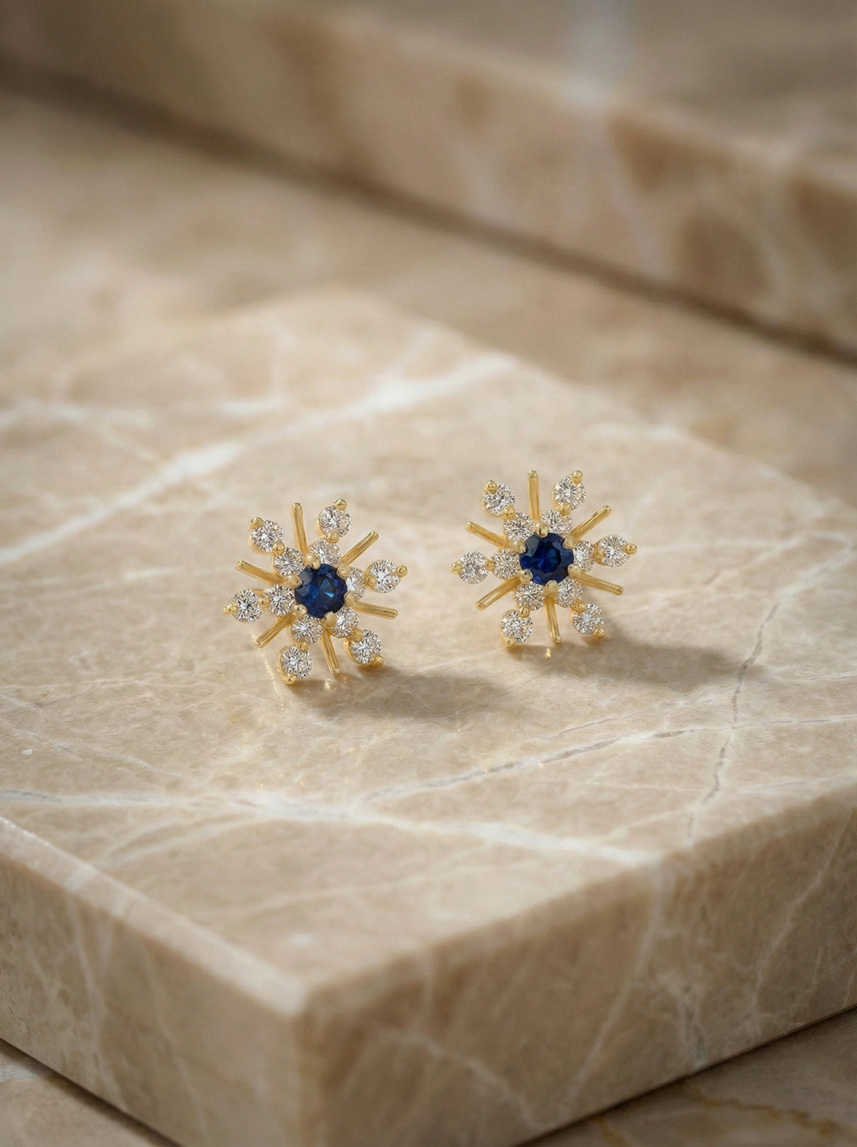 18k gold plated earrings with blue gemstones on a marble surface