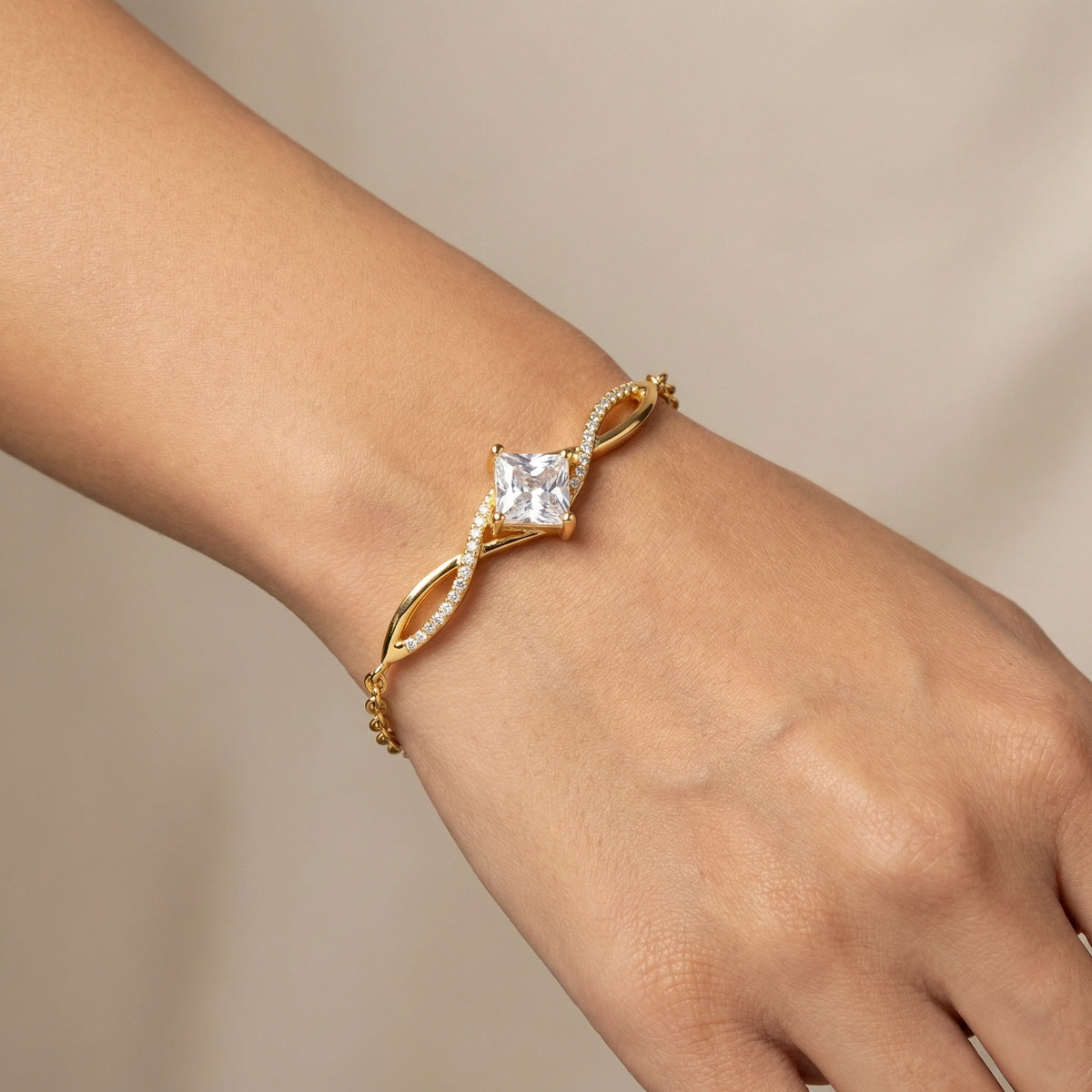 18k gold plated bracelet with a diamond on a wrist against a neutral background