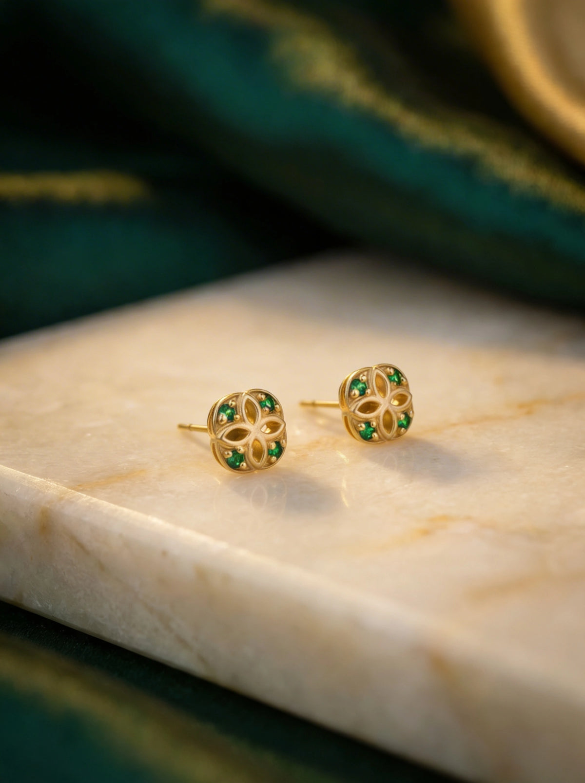 18k gold plated earrings with green gemstones on a marble surface