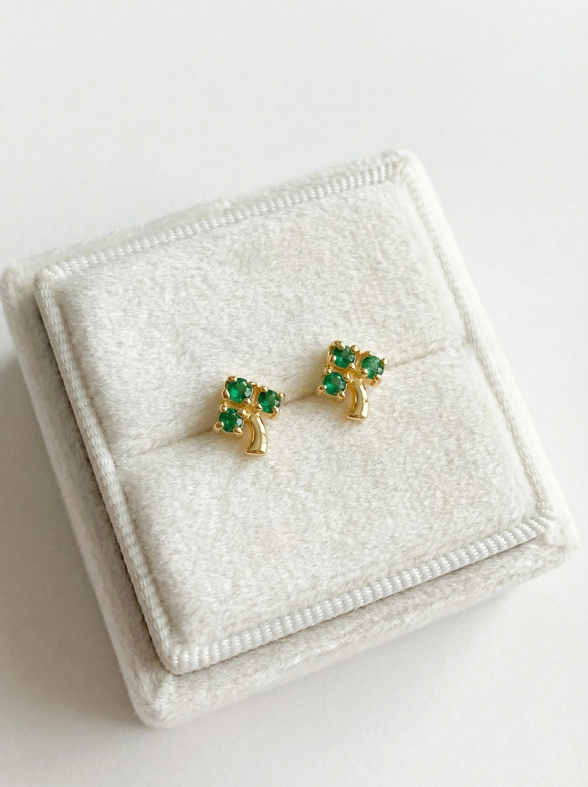 18k gold plated earrings with green gemstones on a white jewelry box