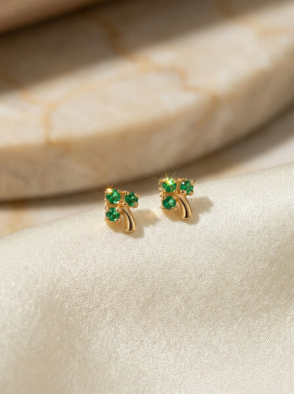 18k Gold plated earrings with green gemstones on a beige fabric background
