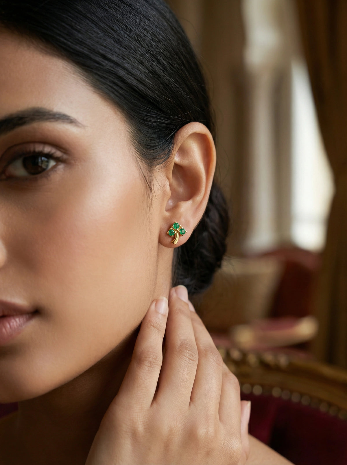 woman wearing green gemstone 18k gold plated earrings with a blurred background