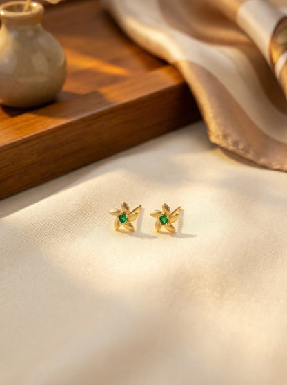 18k Gold plated earrings with green gemstones on a soft fabric background
