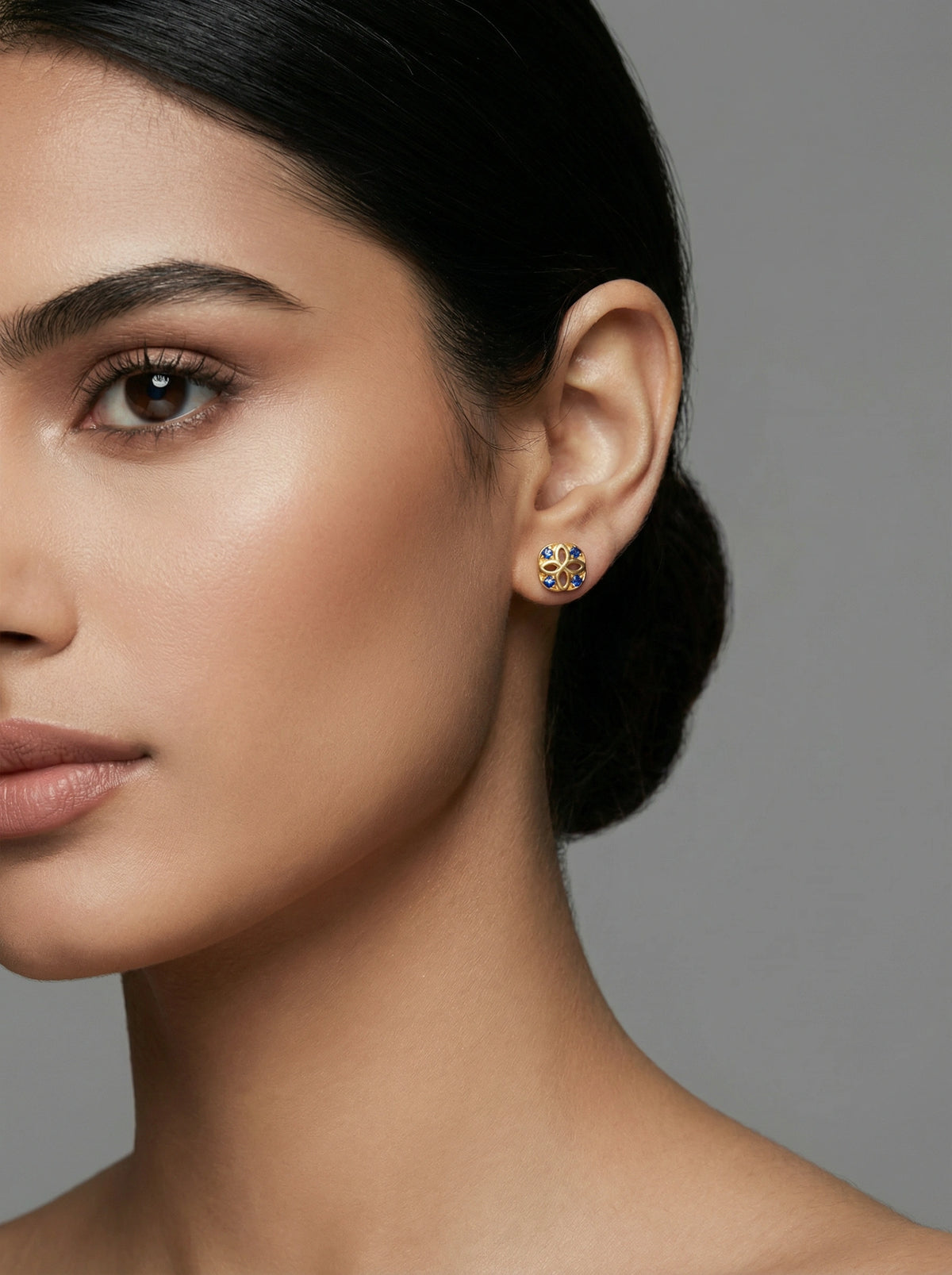 close-up of a woman wearing 18k gold plated earrings with a neutral background