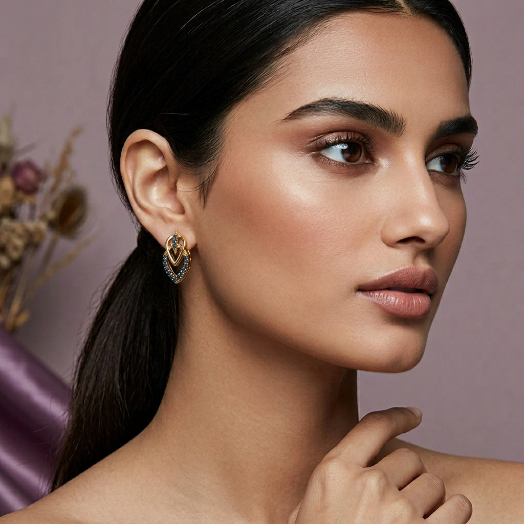 close-up of a woman wearing 18k gold plated earrings with a blurred background
