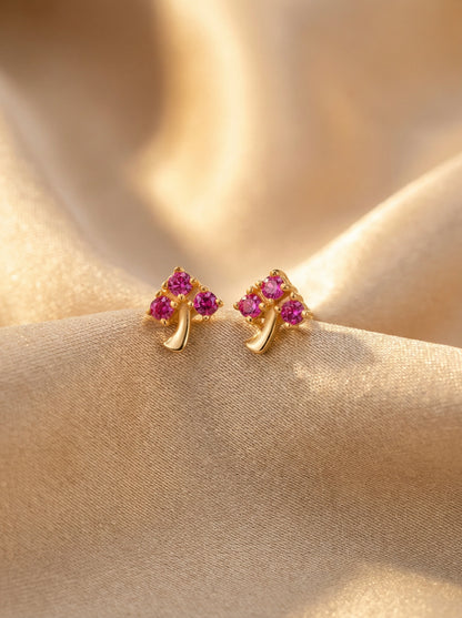 18k Gold plated earrings with pink gemstones on a beige fabric background