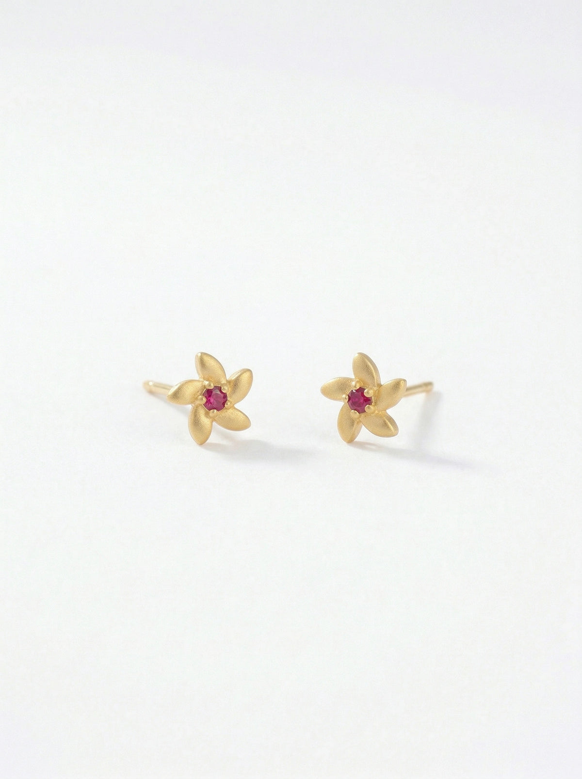 18k Gold plated flower-shaped earrings with red gemstones on a white background