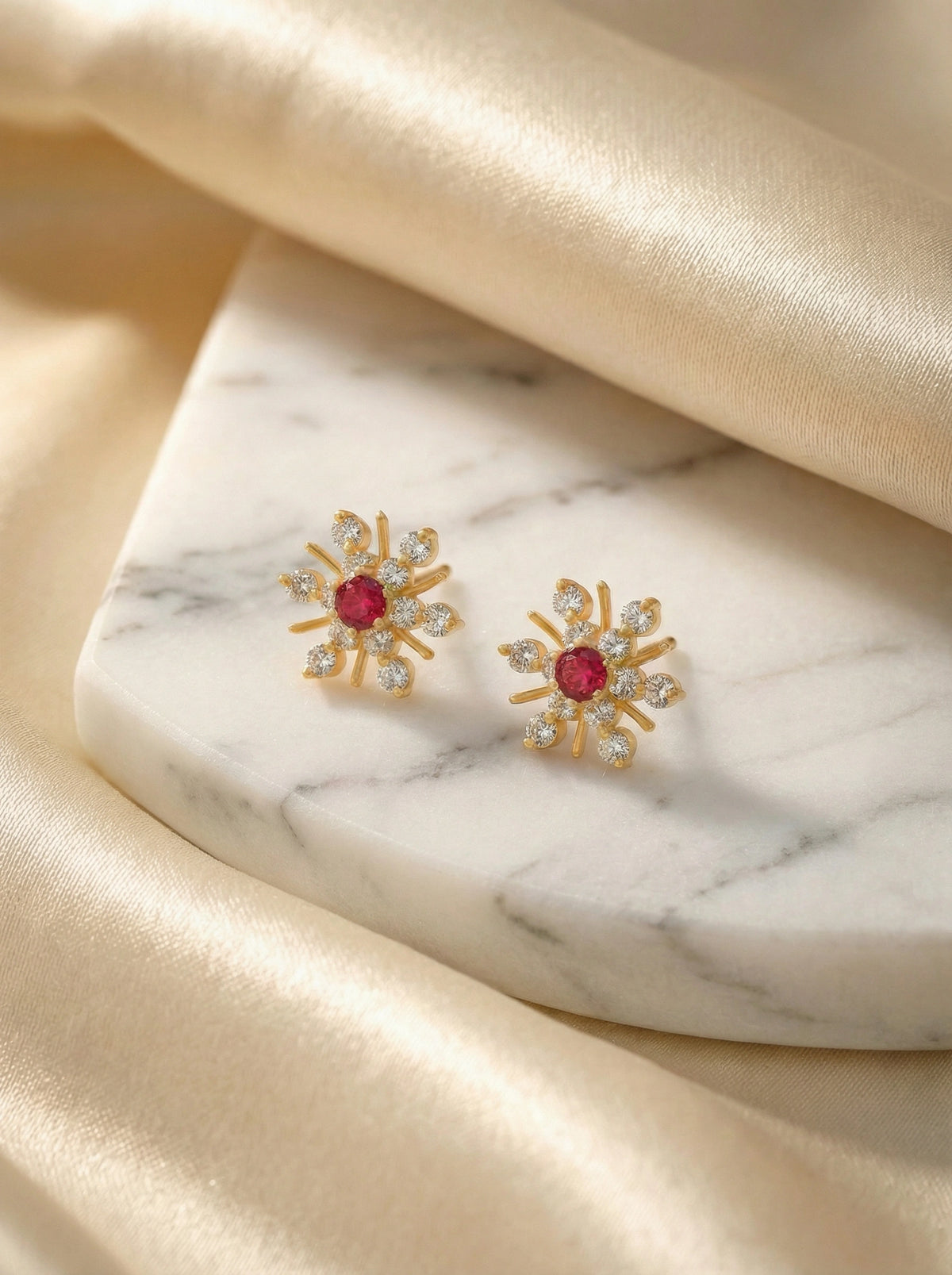 18k Gold plated earrings with red gemstones on a marble surface