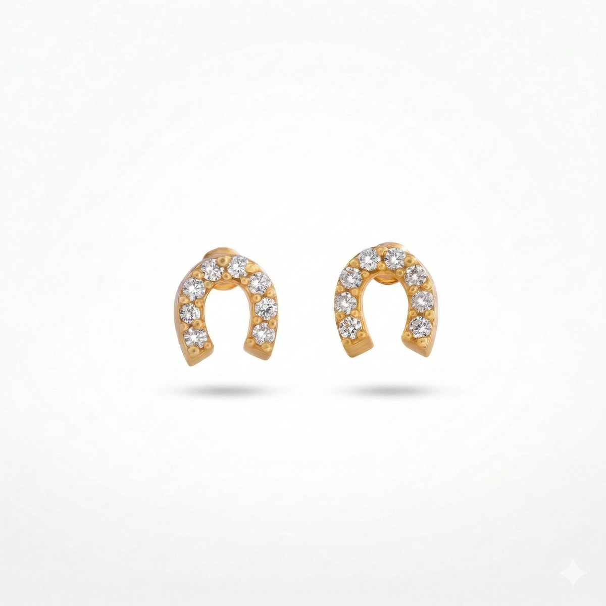 gold horseshoe-shaped earrings with embedded stones on a white background
