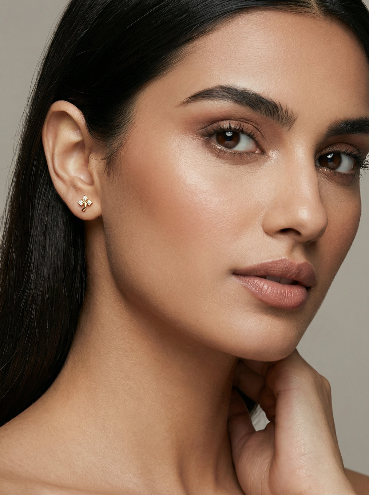 close-up of a woman wearing a 18k gold plated  earring against a neutral background