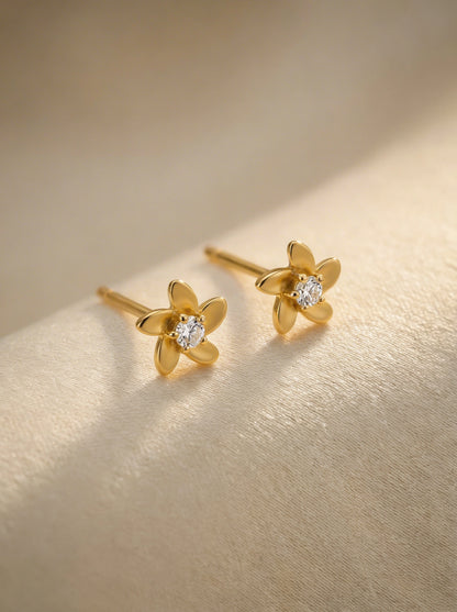  18k Gold plated flower-shaped earrings with diamond centers on a gold background