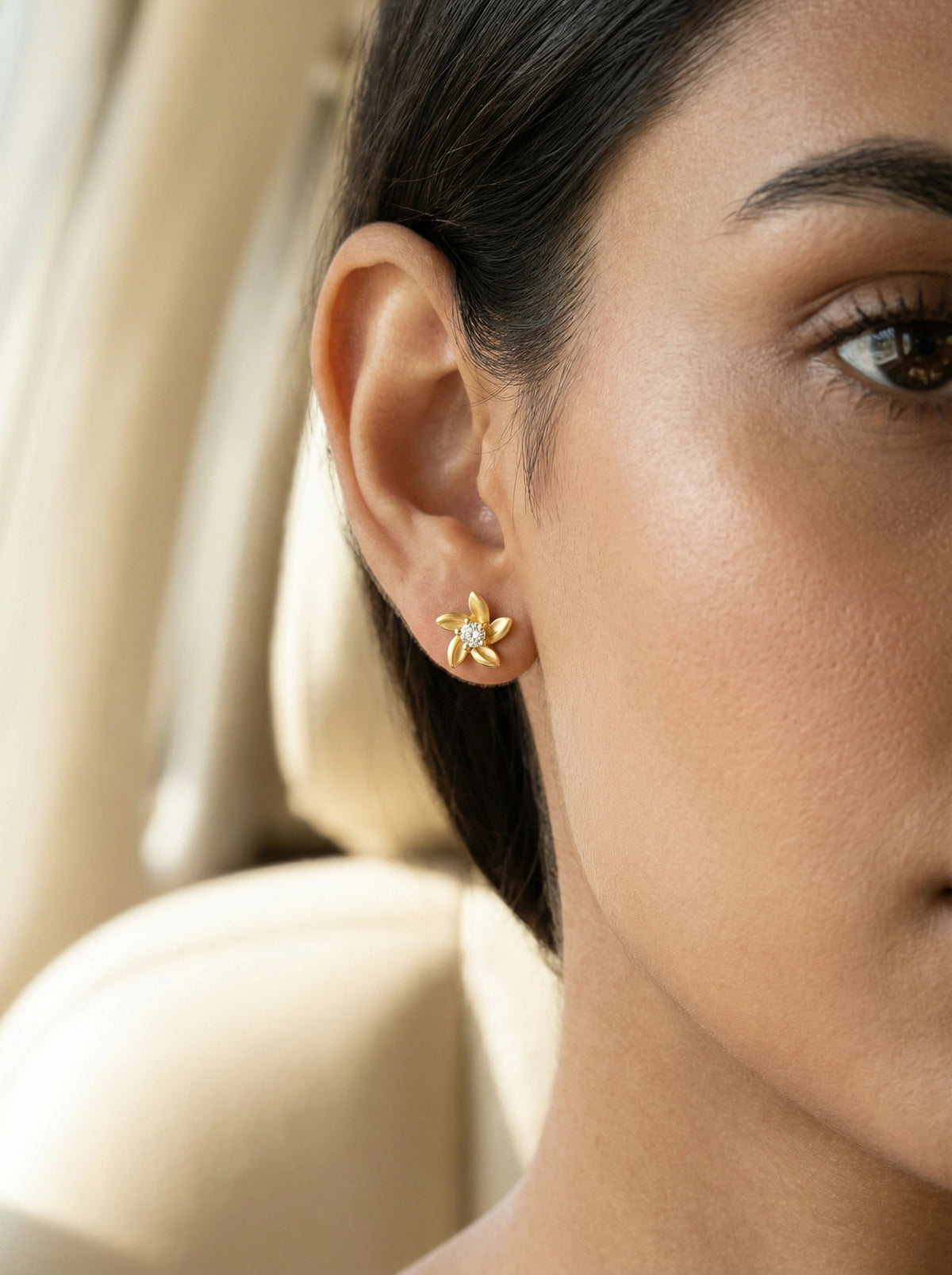 close-up of a woman wearing a 18k gold plated earring with a blurred background