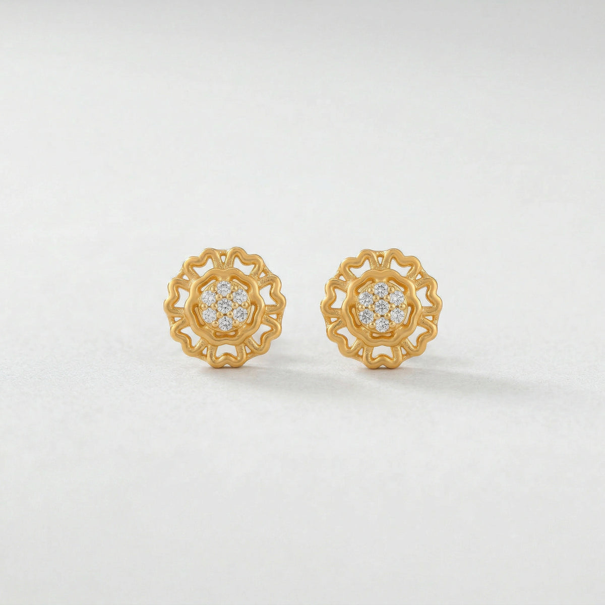 pair of 18k gold plated earrings with diamond accents on a light gray background