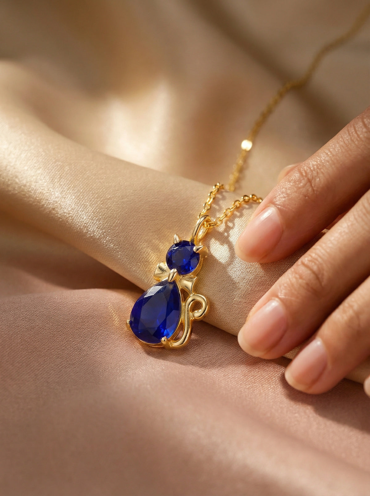 18k gold plated necklace with blue teardrop-shaped gemstones on a soft beige background