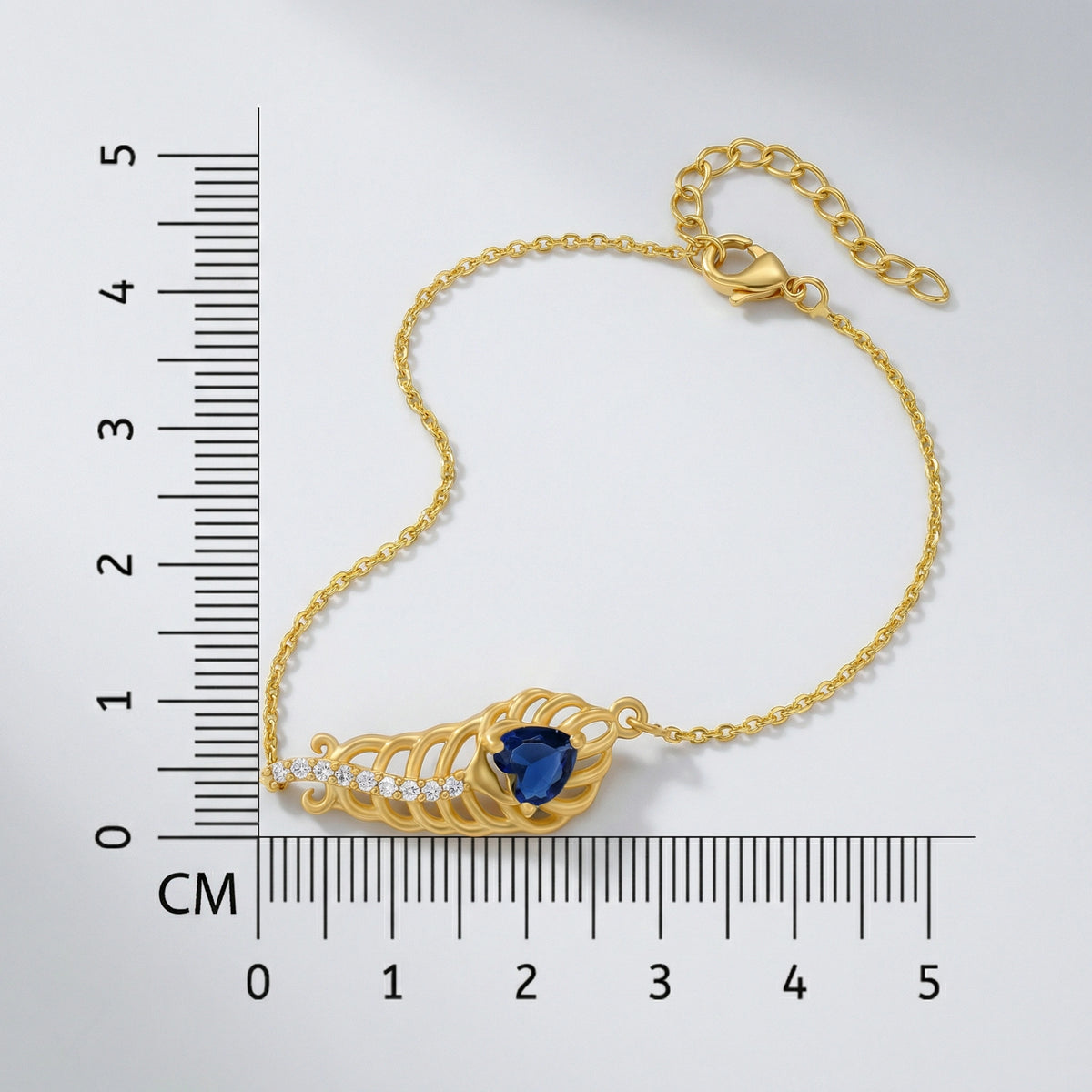 18k Gold plated bracelet with a blue gemstone next to a ruler for measurement on a white background