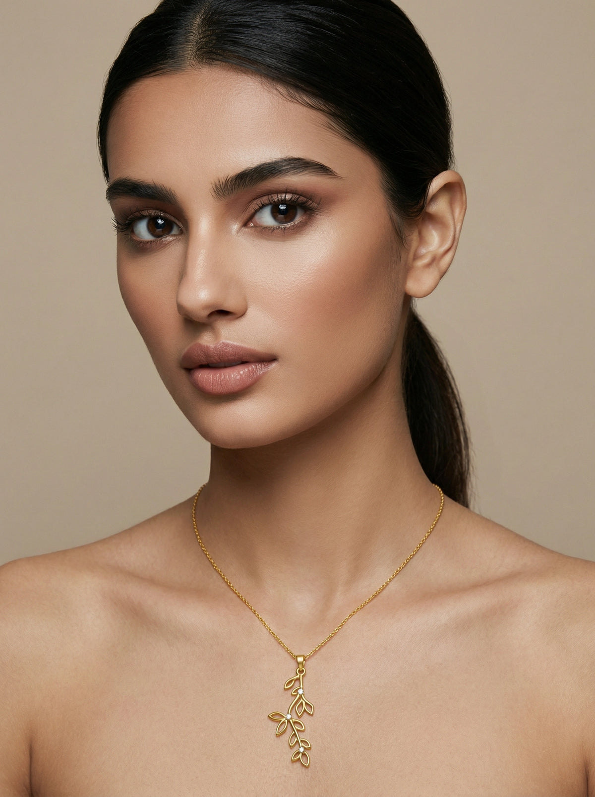 woman wearing a 18k gold plated necklace against a beige background