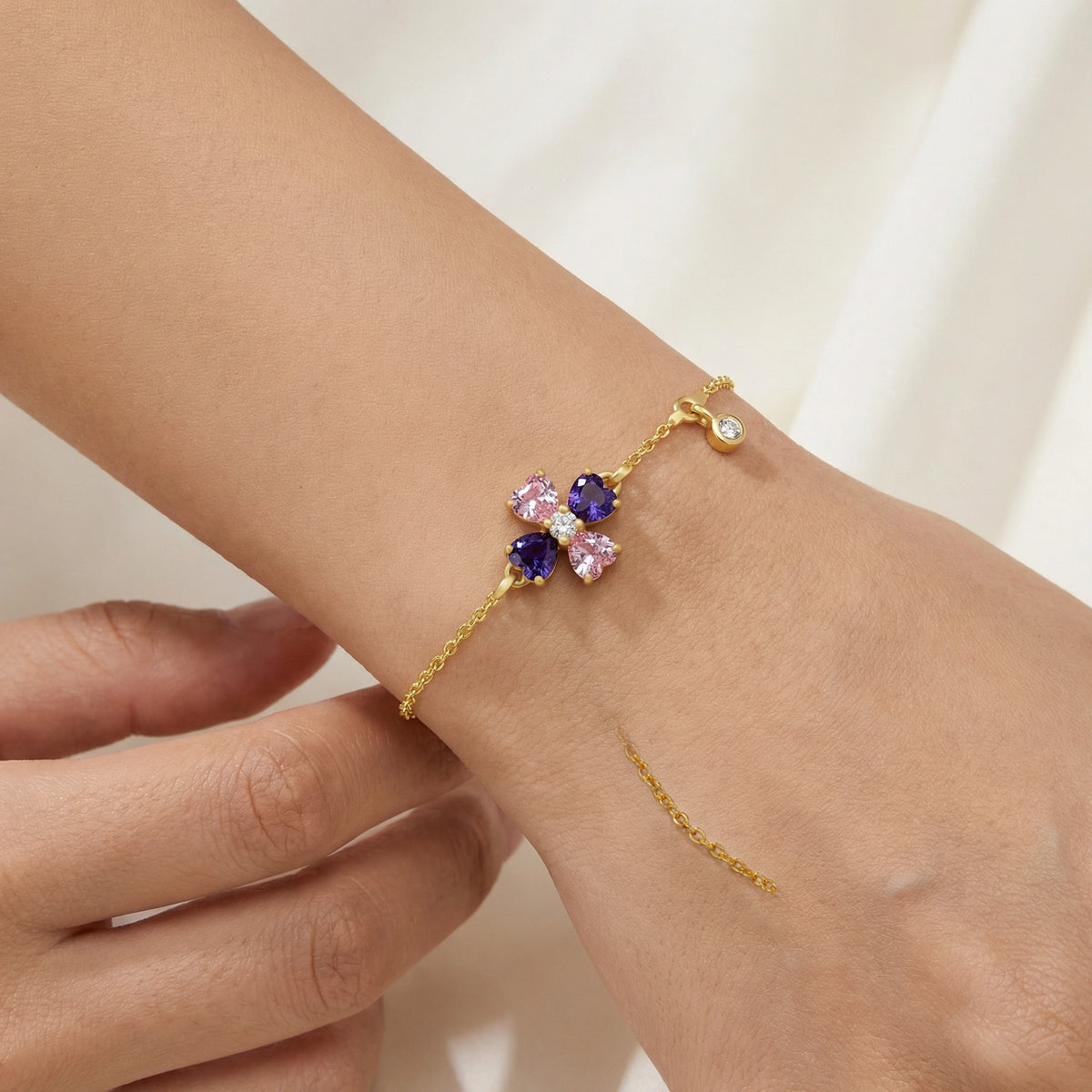 18k gold plated bracelet with floral design featuring pink and purple stones on a wrist.