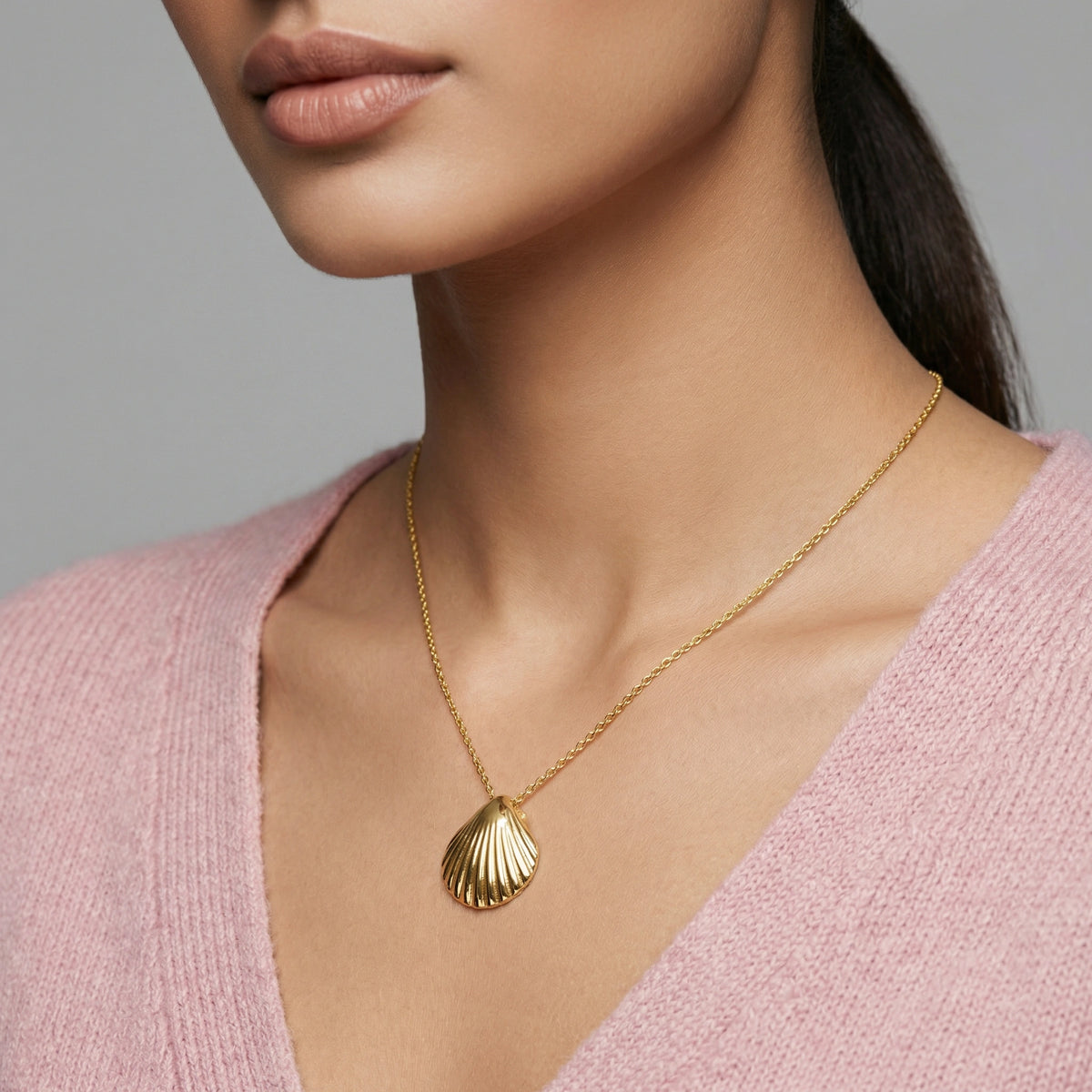 18k gold plated necklace with a shell pendant worn by a person in a pink sweater.